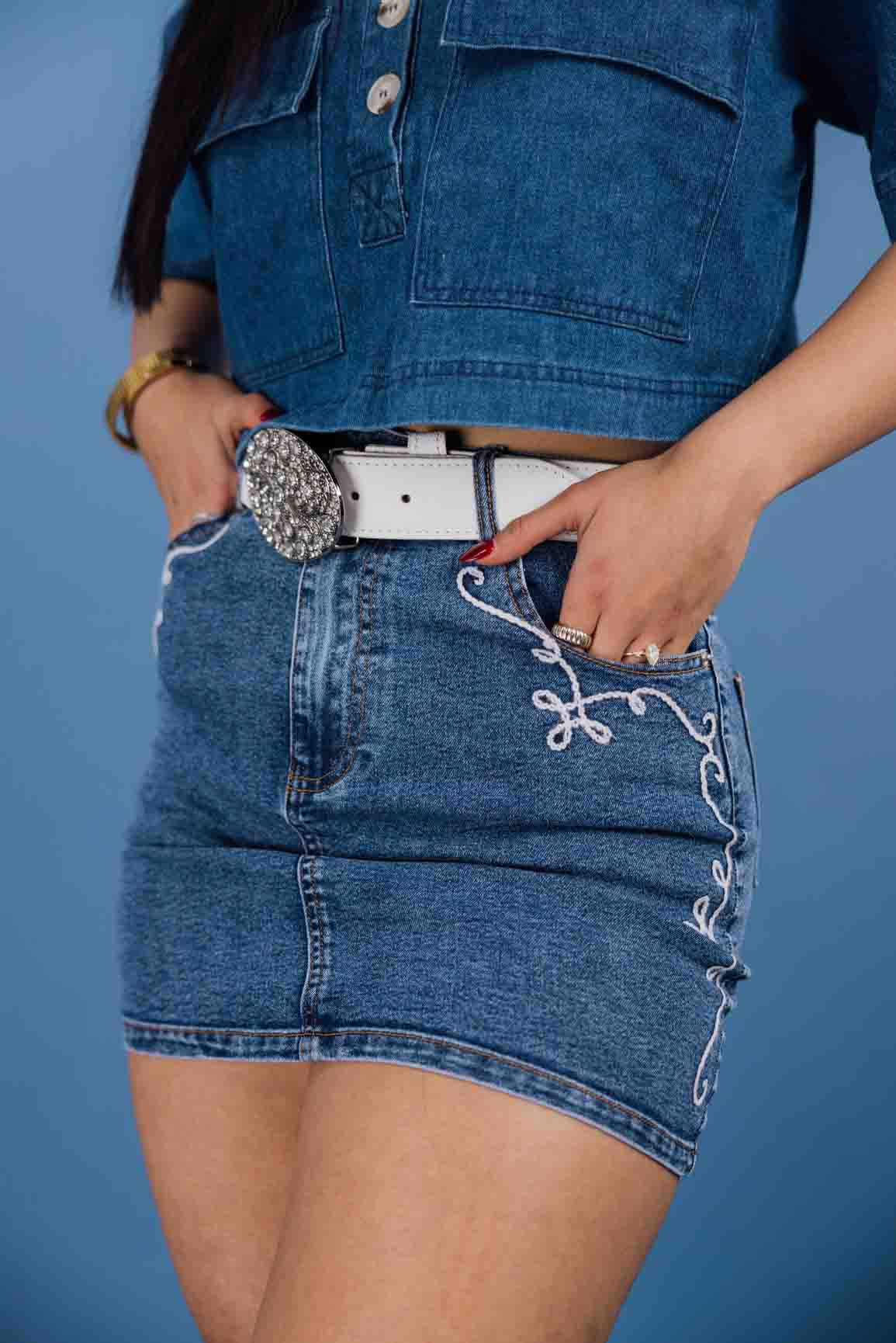 This mid-rise mini skirt features embroidered pocket details.