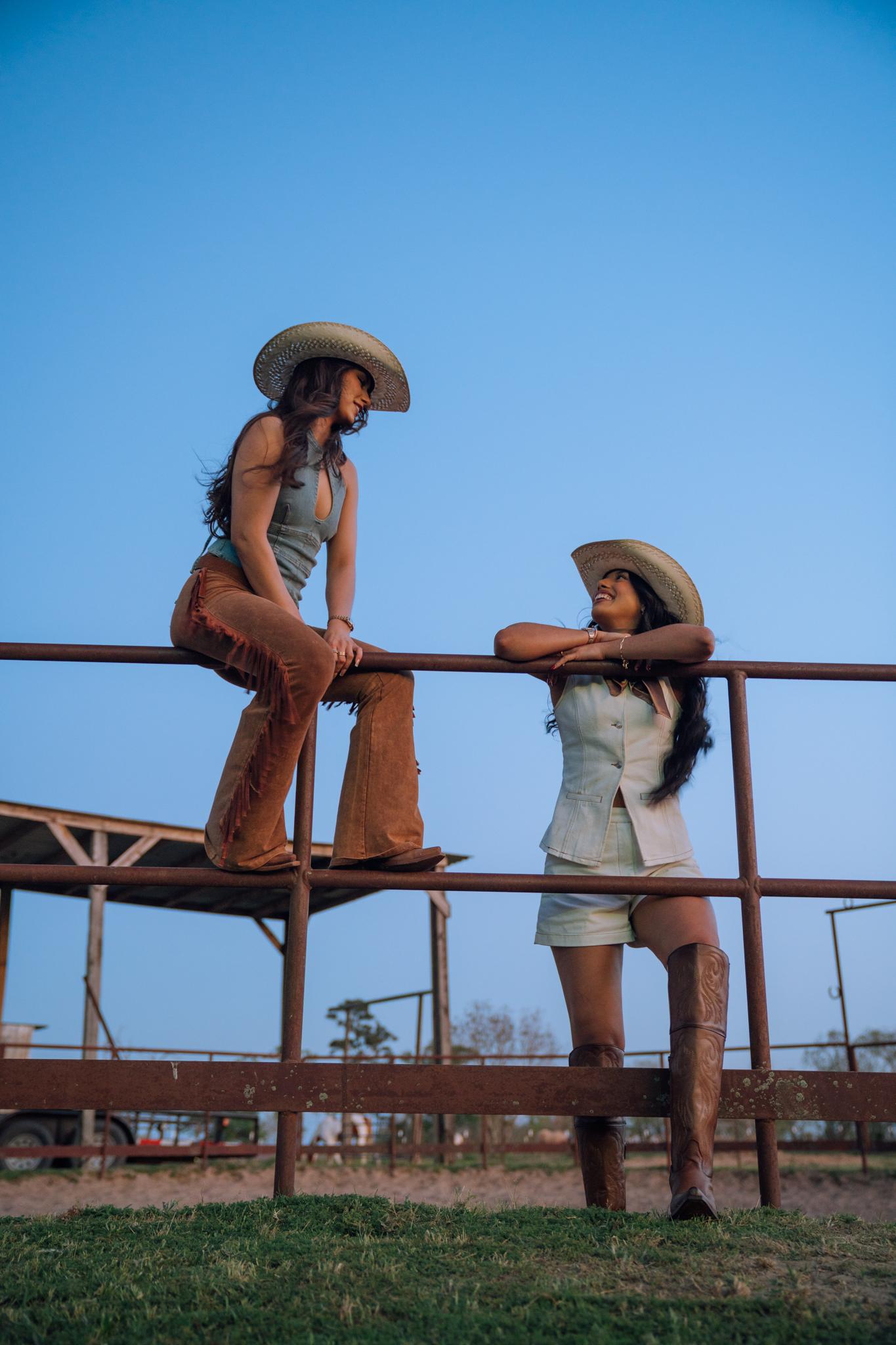 Two women looking at each other while wearing Rock'em straw hats