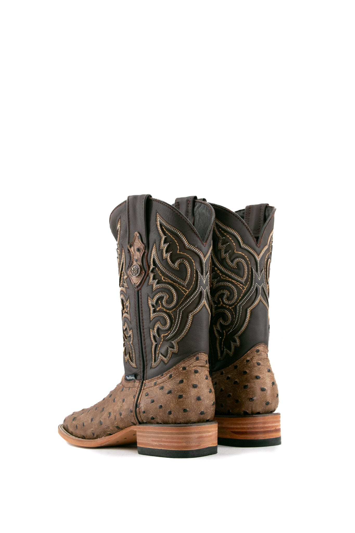 Back view of The Ostrich Matte Rustic boots in saddle brown with a square toe, ostrich quill texture, brown leather shaft with brown embroidery, and stacked heel.