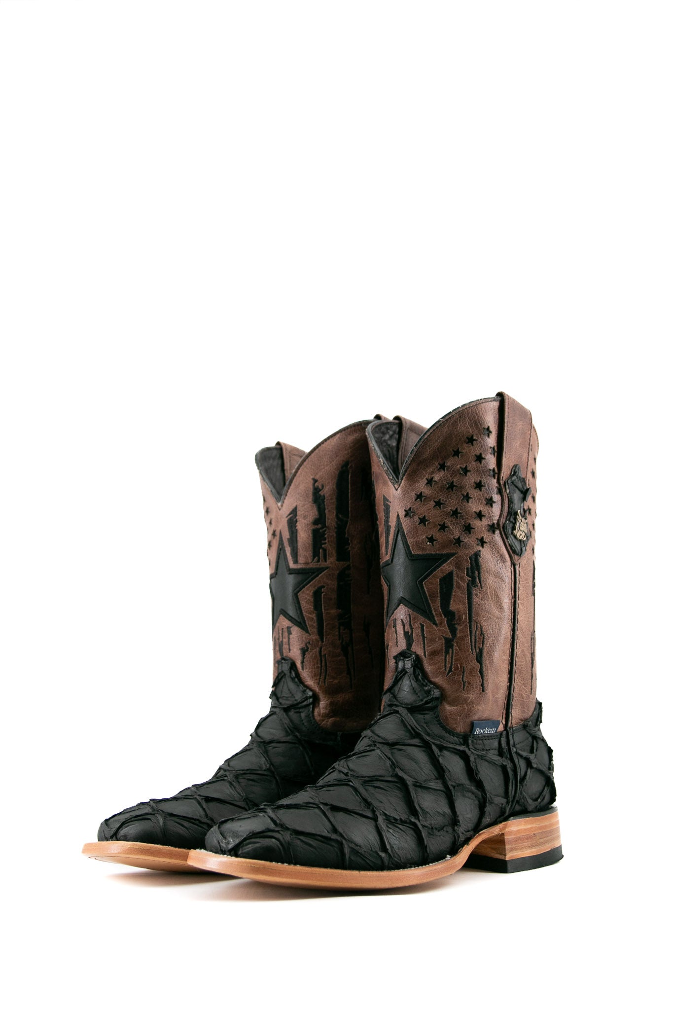 The black Clone Fish Pirarucu Matte cowboy boots feature a square toe, black pirarucu print vamp, brown embroidered shaft with black star perforations, and a rubber hee