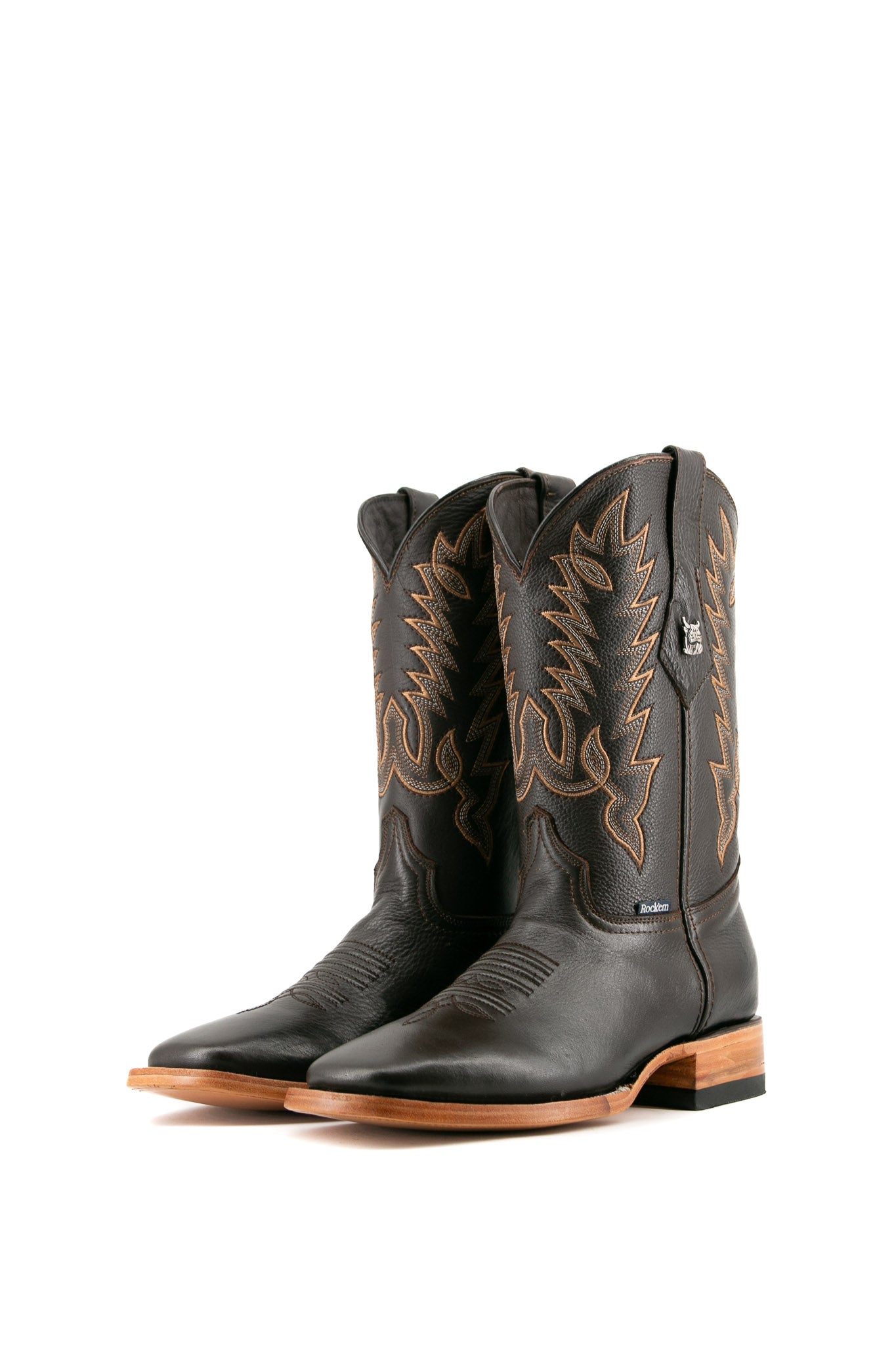The Heritage Rainbow cowboy boots feature brown leather with intricate stitching and embroidery, a Rock'em bull emblem, durable leather sole, and rubber heel.