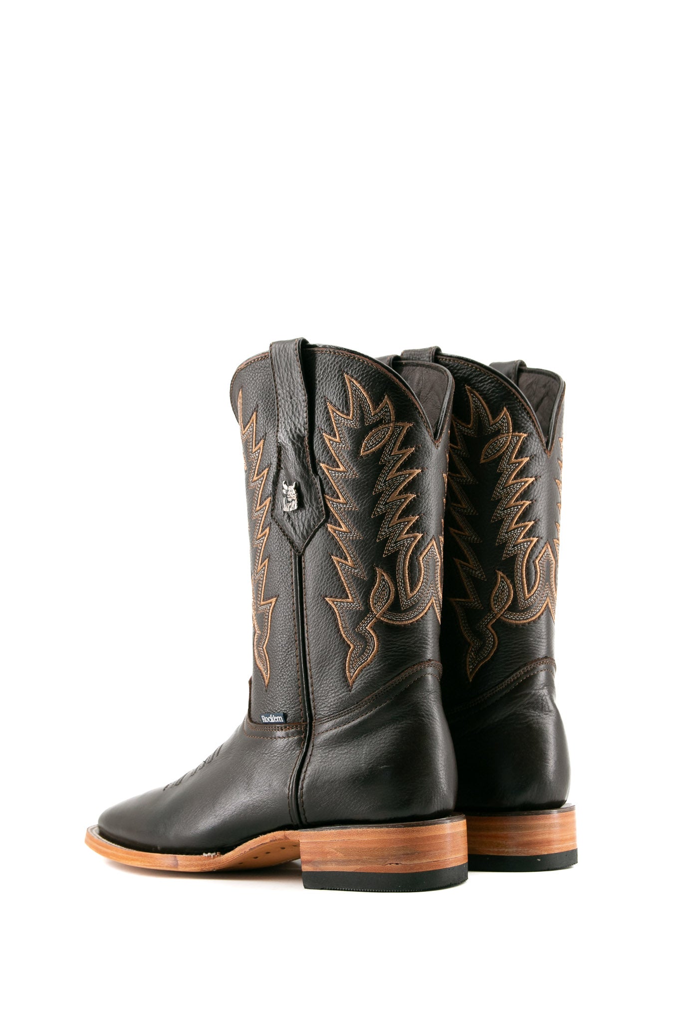 The Heritage Rainbow cowboy boots feature brown leather with intricate stitching and embroidery, a Rock'em bull emblem, durable leather sole, and rubber heel.