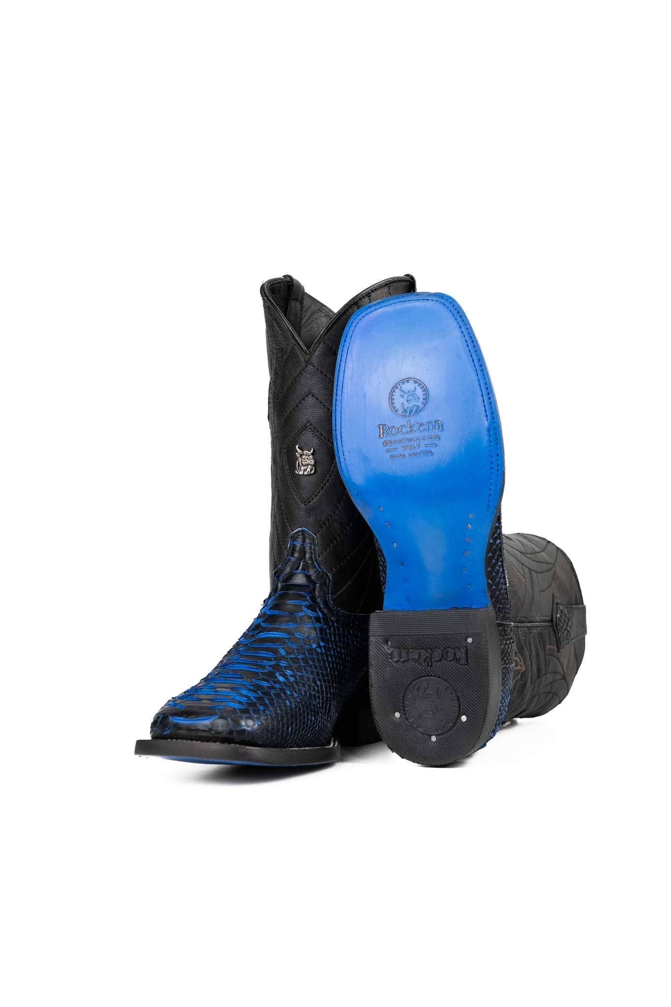 View of the Python Exotic Cowboy Boots in Blue/Black. Made from genuine leather, blue and black python-print vamp, square toe, and an embroidered shaft. Finished with a durable rubber heel and a blue sole.