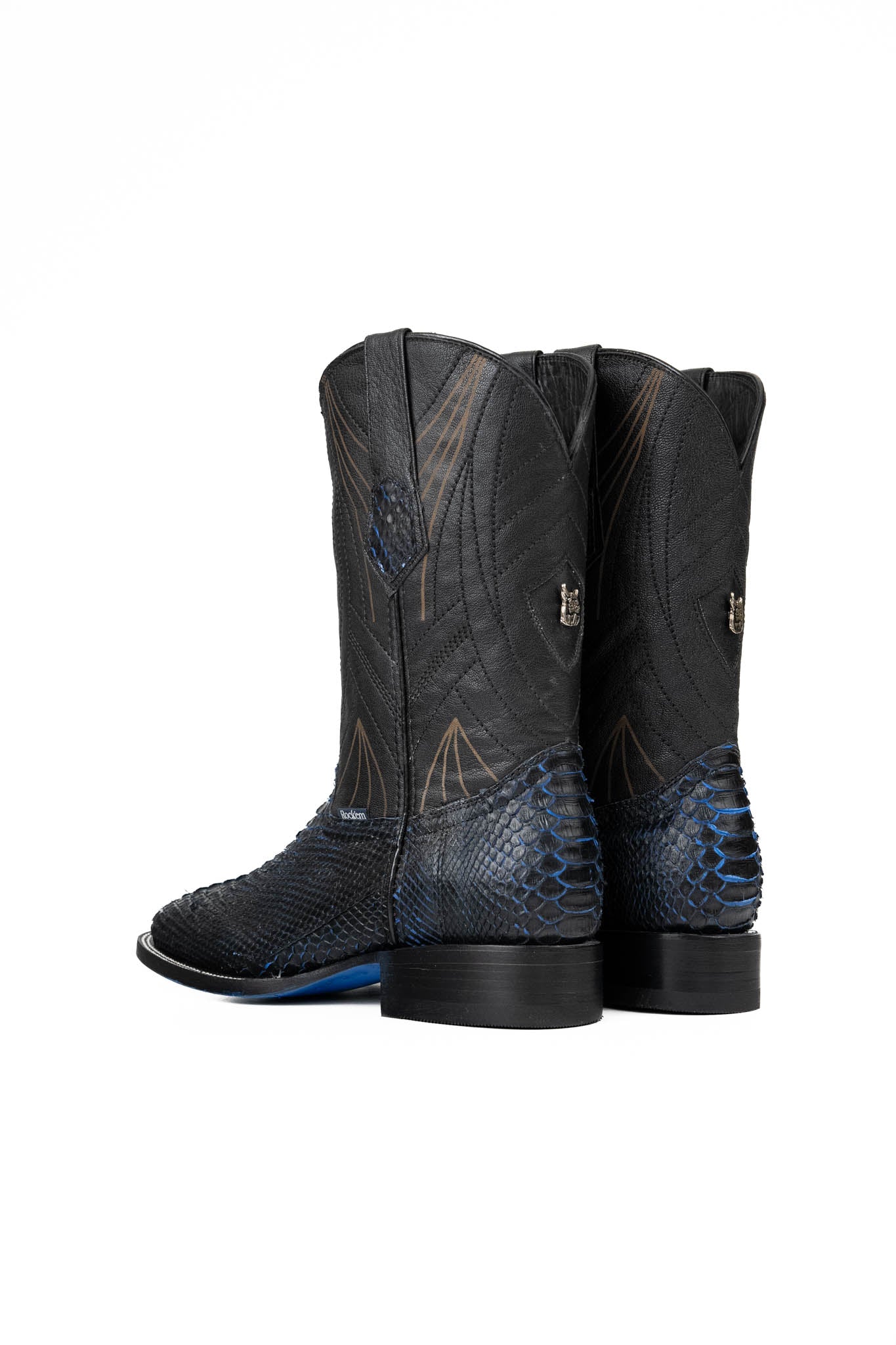 Back of the Python Exotic Cowboy Boots in Blue/Black. Made from genuine leather, blue and black python-print vamp, square toe, and an embroidered shaft. Finished with a durable rubber heel and a blue sole.