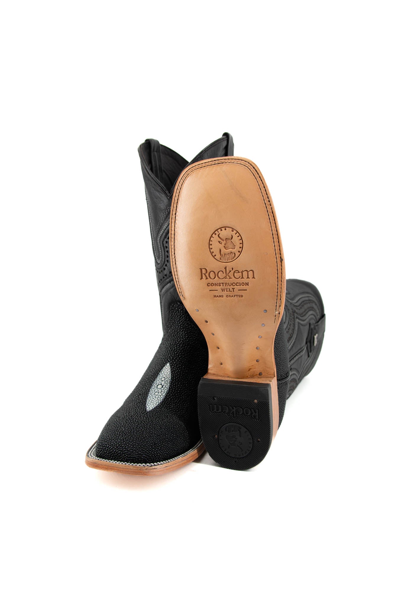 View of the Barnet Stingray Exotic in an all-black cowboy boot crafted from genuine leather. It showcases a square toe, an exotic stingray vamp with pebbled texture and a white diamond-shaped marking in the middle, embroidered leather shaft, rubber heel, and leather sole.