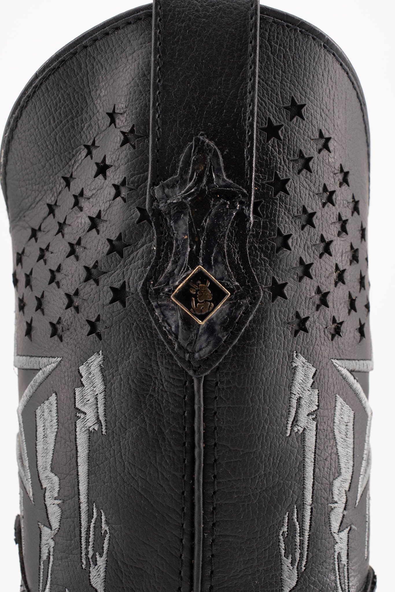 Closer view of the side shaft in smooth black leather, featuring a patchwork design with a star, star-shaped perforations, and a small metallic Rock'em bull's head on the pull strap.