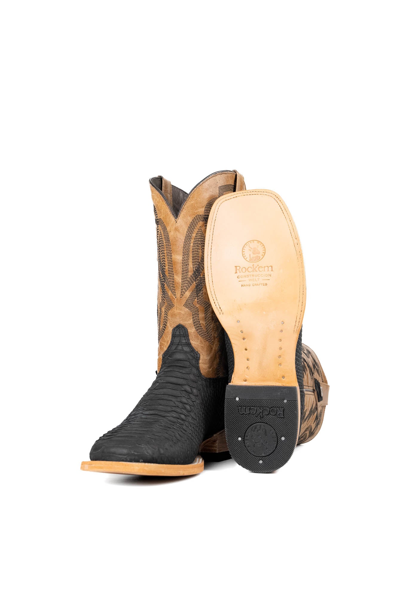 View of the Renegate Python boot in matte black featuring a black Pirarucu fish print vamp, tan leather shaft with embroidery, a square toe, and leather sole. 