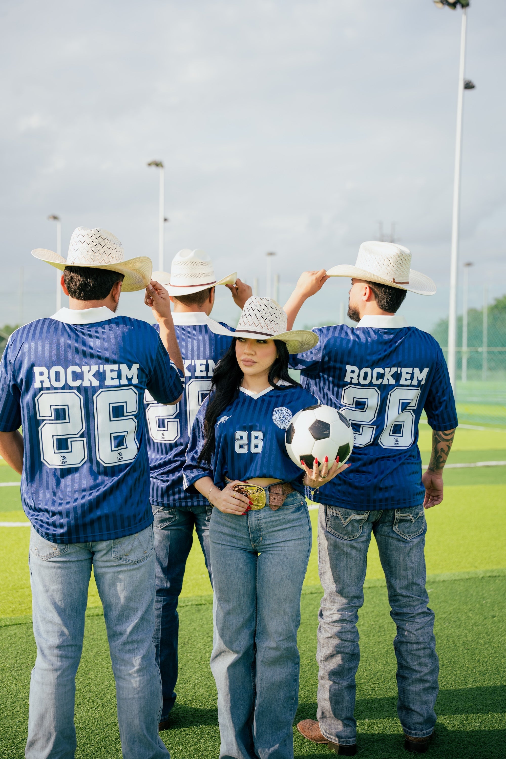 Group of people wearing blue jerseys with 'Rockem' and number '26', standing on a sports field.