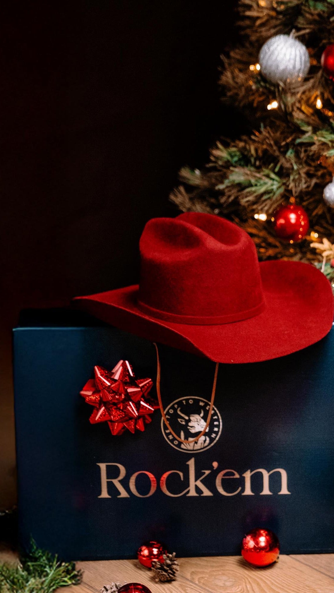 Christmas tree with decorative lights, boots, and 'Rock'em' branded boxes on a wooden surface.
